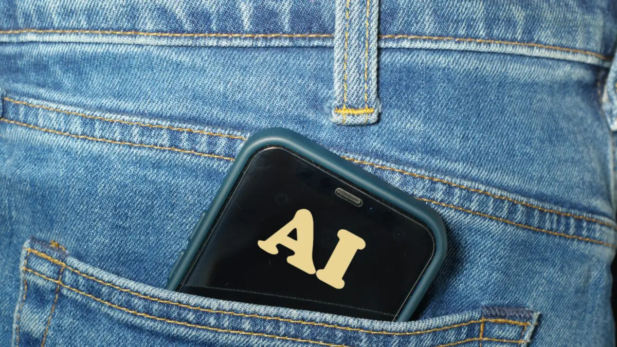 Phone showing the letters AI on its screen, tucked into a jeans back pocket