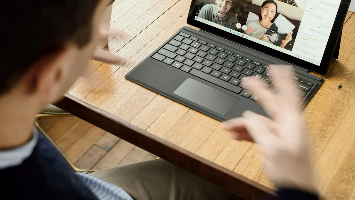 Coach on a video call with a client, working from a laptop at a desk
